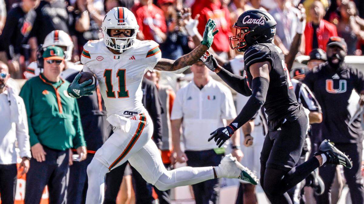 Miami Hurricanes wide receiver Samuel Brown (11) evades a tackle by Louisville Cardinals defensive back M.J. Griffin (26) in the second half during an NCAA football game at L&N Federal Credit Union Stadium in Louisville, Kentucky on Saturday, October 19, 2024.