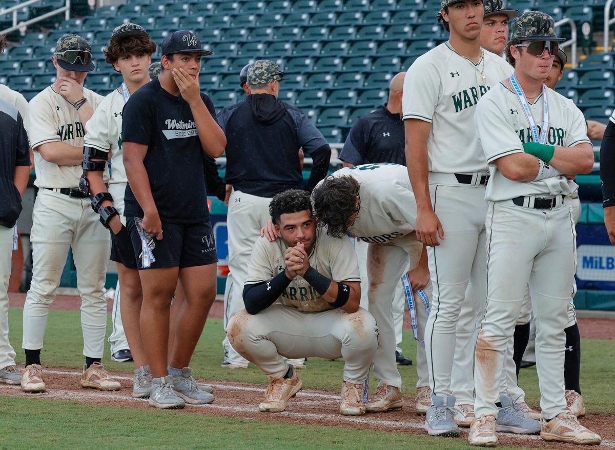 `Westminster Christian School Warriors William Alvarez (17) squats as he watches North Broward Prep Eagles receive the championship trophy after the Eagles defeat the Warriors in the FHSAA Baseball Class 3A State Final at Hammond Stadium in Fort Myers, Florida on Wednesday, May 22, 2024.