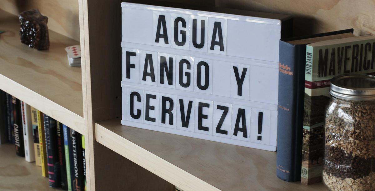 Hialeah, Florida, February 25, 2020- A sign in Spanish that reads, water, mud and beer graces one of the shelves in a seating area at Unbranded Brewery. Unbranded is a new beer brewery in Hialeah, and it’s yet another sign of Hialeah developing into a place that’s attracting folks from outside the city as an entertainment spot.