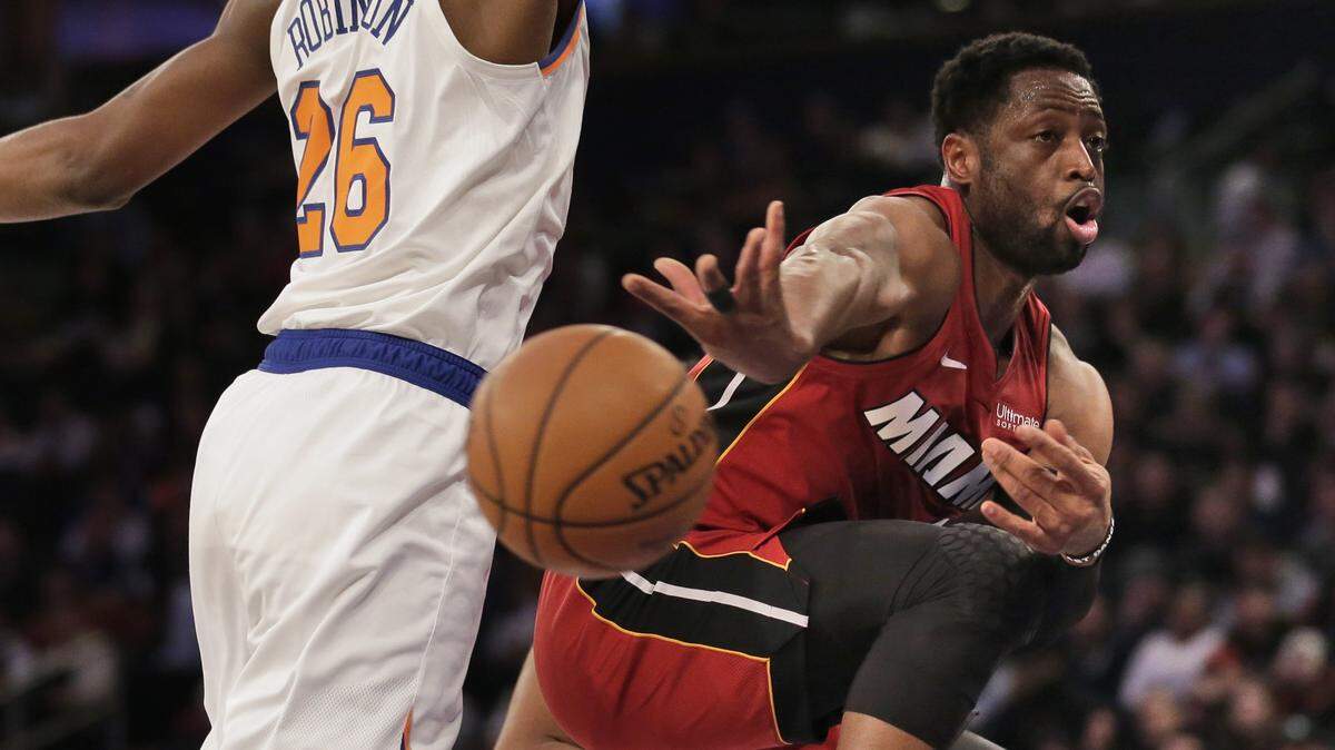 Miami Heat’s Dwyane Wade, right, passes around New York Knicks’ Mitchell Robinson during the first half of the NBA basketball game, Sunday, Jan. 27, 2019, in New York.