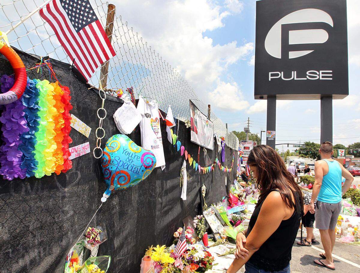 Mourners pay their respects to the victims of the Pulse nightclub shooting by leaving flowers, photos, messages and candles in front of the building in Orlando, Florida.