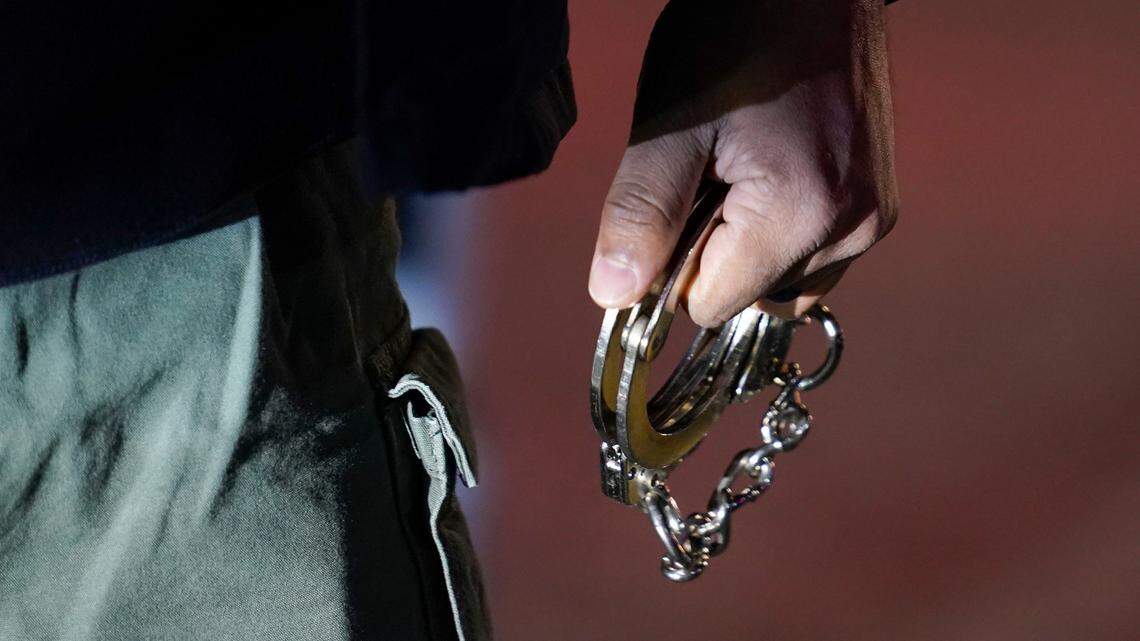 In this photo, a police officer carries handcuffs before a raid in the Brooklyn borough of New York, Tuesday, Jan. 4, 2022. A man impersonated a state trooper and tried paying a woman for sex, Massachusetts state police said. He threatened to arrest her if she didn’t comply. 