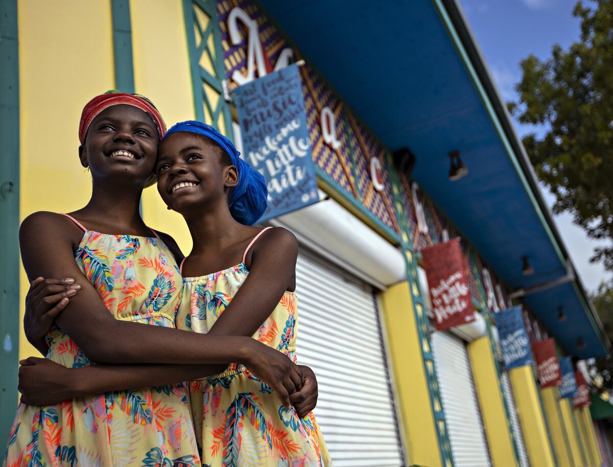 Sisters Tah’Siah, 13, left, N’Deirah,12, right, pose outside the Little Haiti Cultural Complex’s Caribbean Marketplace while taking a break from helping out at their father’s Via Vegan booth in June. The cultural center and market are a hub of cultural and social activities and tourism in Little Haiti.