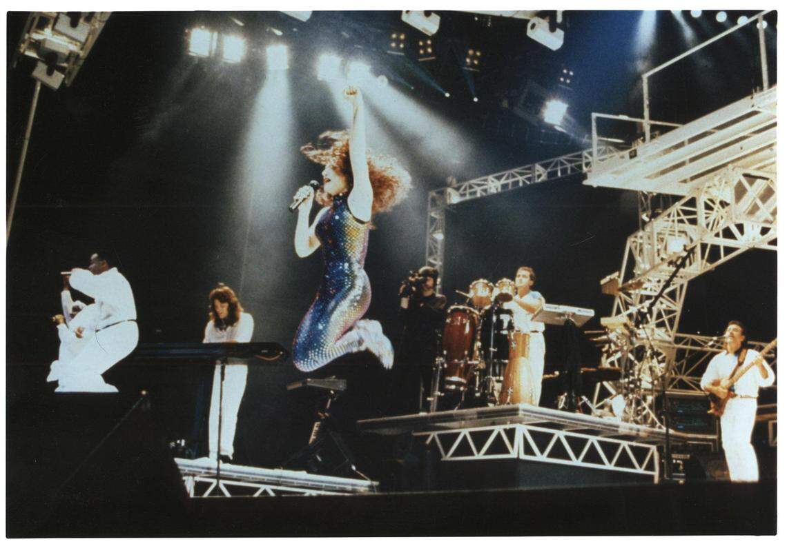 Gloria Estefan entertains on stage accompanied by her band and back-up singers, just one year after her bus accident.