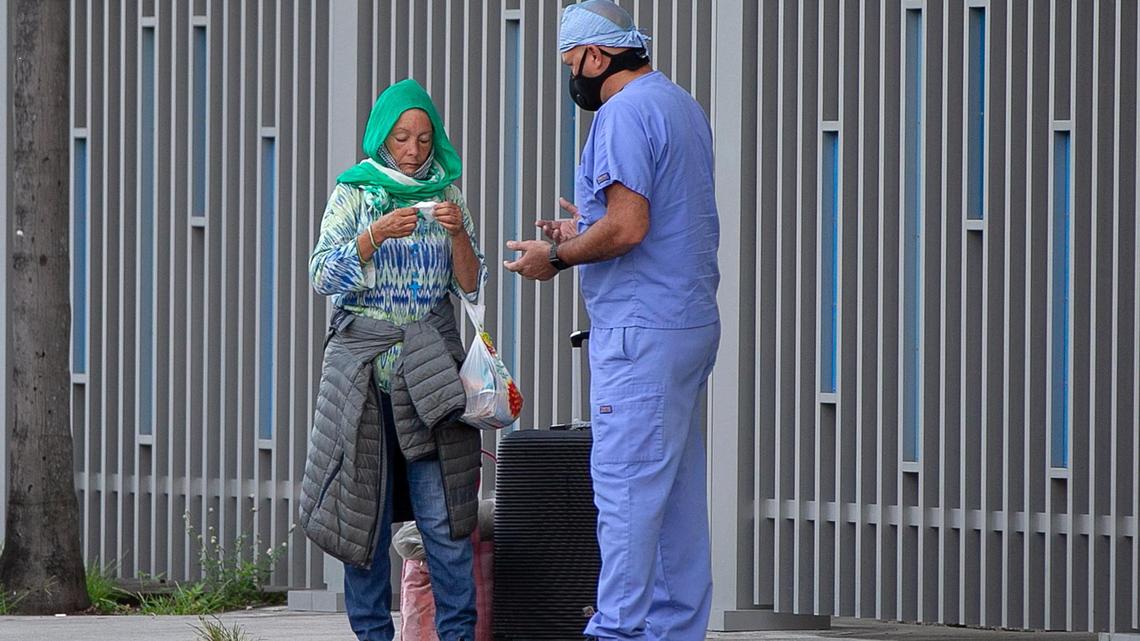 Camillus House staff Medical assistant Aldo Fleites checked on a homeless woman standing on the side walk by the Jackson Memorial Hospital during the COVID-19 pandemic in 2020.