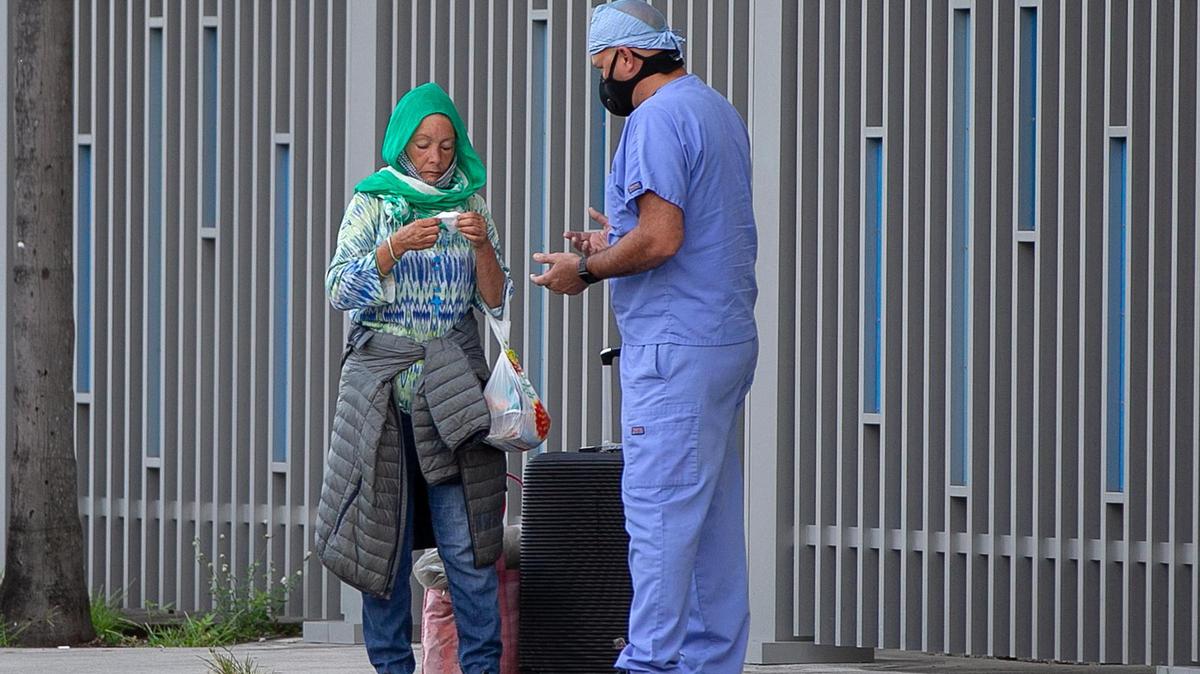 Camillus House staff Medical assistant Aldo Fleites checked on a homeless woman standing on the side walk by the Jackson Memorial Hospital during the COVID-19 pandemic in 2020.