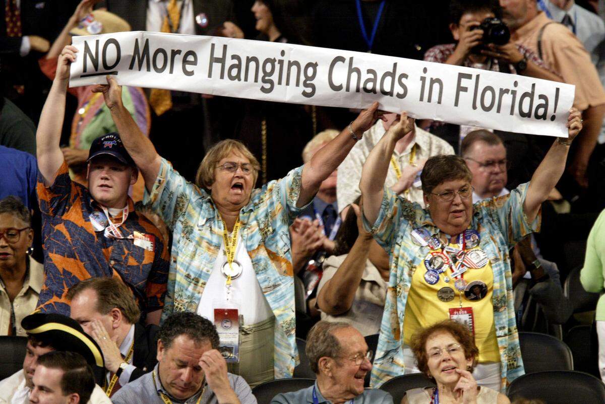 Democratic National Convention delegates unveil a banner 26 July, 2004, at the FleetCenter in Boston, Massachusetts. The banner recalled the mired 2000 election which made the hanging chad a popular term.