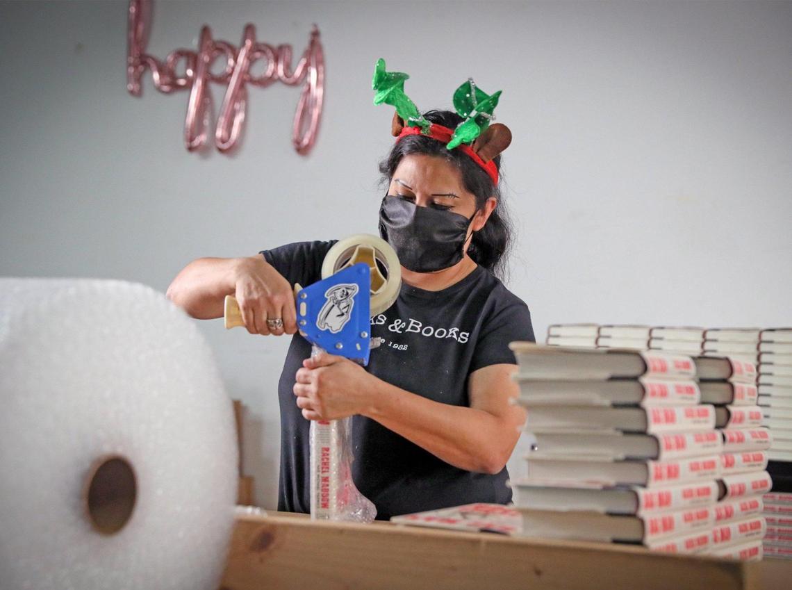 Books & Books employee Ana Guerra packs books in bubble wrap as she fulfills holiday orders that are shipping out of the company warehouse on Thursday, December 17, 2020.
