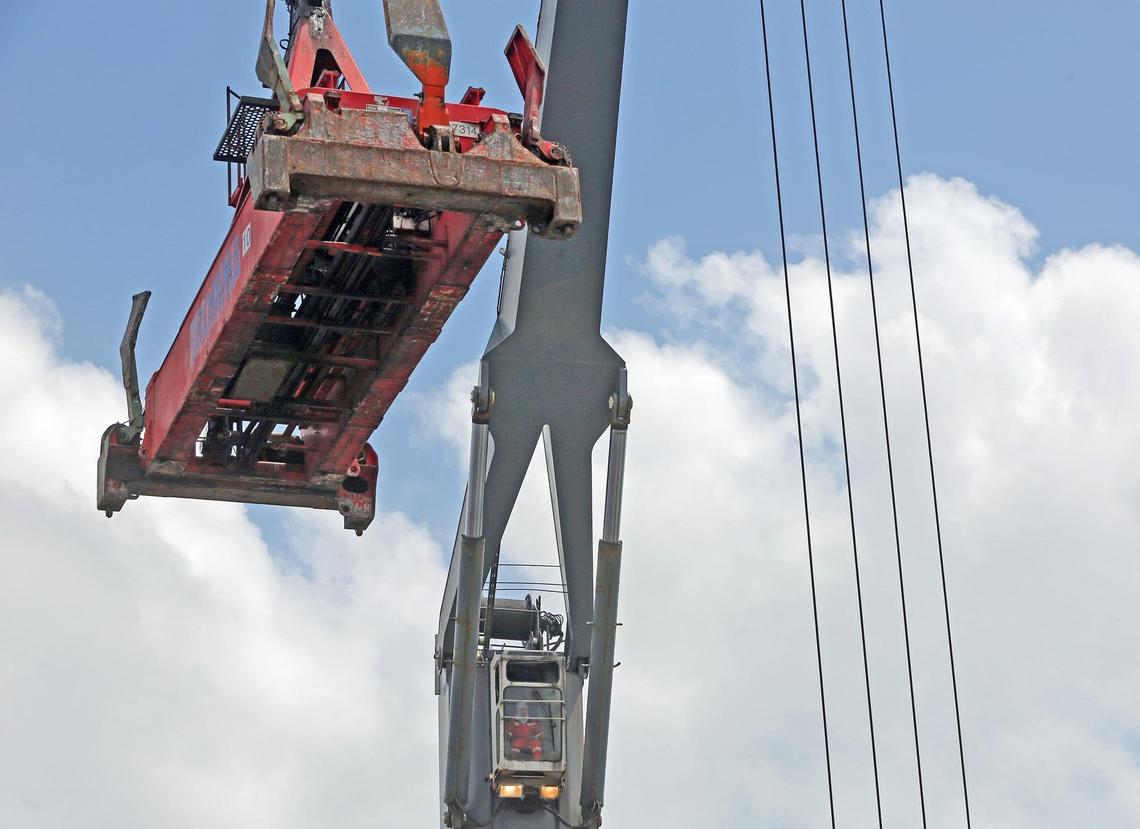 A crane operator sits high on a Seaboard Marine ship with a built-in crane system that loads and offloads containers at PortMiami.