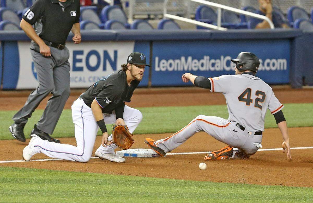 Miami Marlins Brian Anderson (42) waits for the ball as San Francisco Giants Evan Longoria (42) slides safely into third base in the third inning at loanDepot park in Miami, Florida, Friday, April 16, 2021.