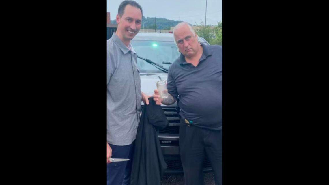 Detectives Bobby Shaw and Eddie Fallert posed with the jar after freeing it from the raccoon.