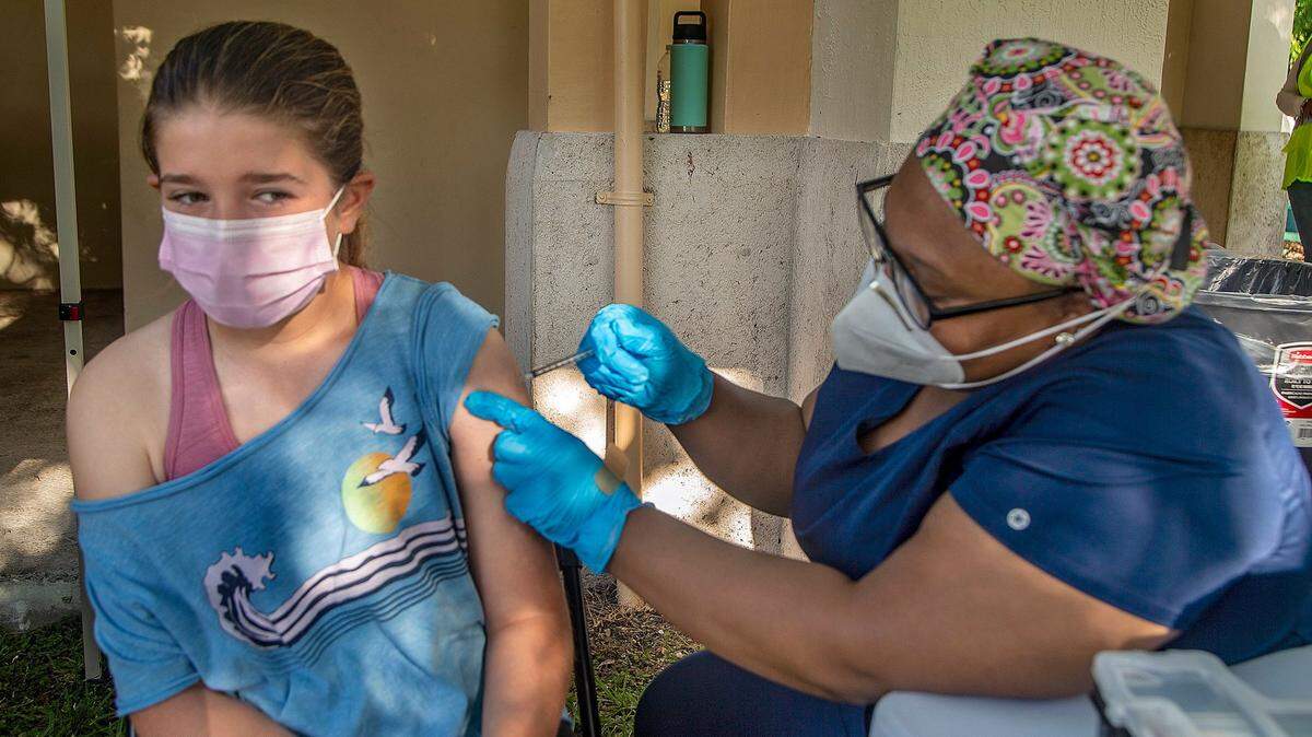 Eva Mcaliley, de 12 años, recibe su primera inyección de la vacuna Pfizer contra el COVID-19 de manos de la enfermera Katiana Legagneur en la South Miami Children's Clinic el 15 de mayo de 2021.