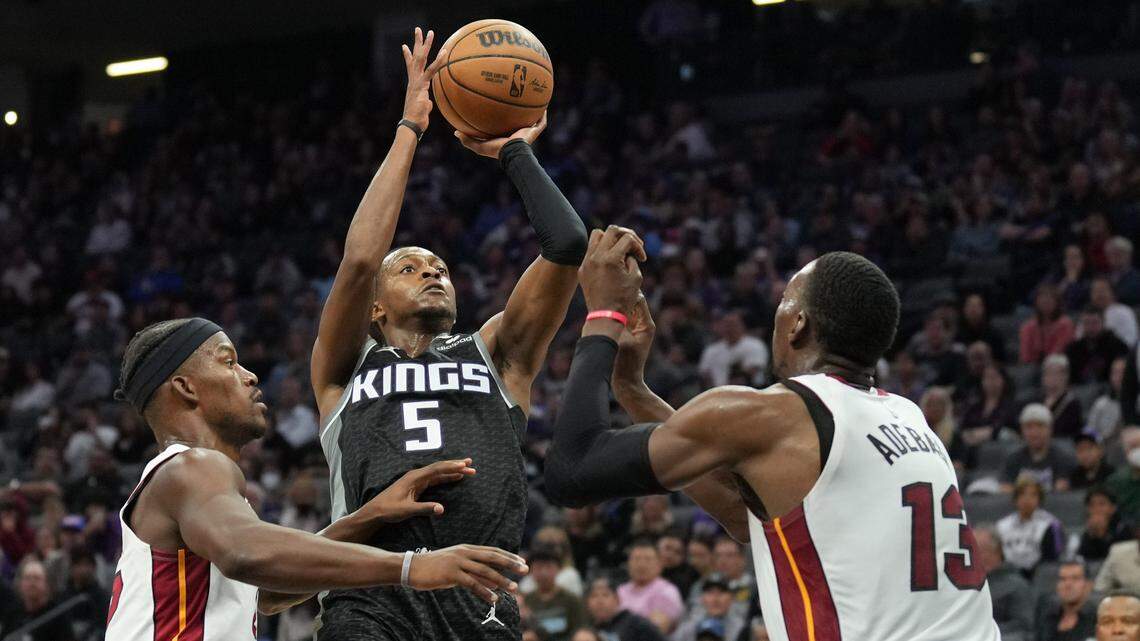 Sacramento Kings guard De’Aaron Fox (5) shoots against Miami Heat forward Jimmy Butler (left) and center Bam Adebayo (13) during the fourth quarter at Golden 1 Center.