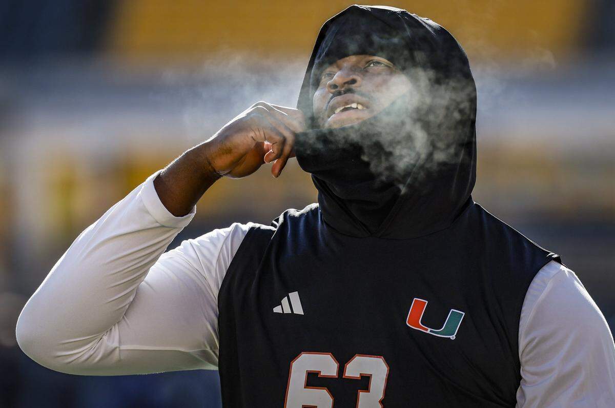 A mist of cold air is seen as Miami Hurricanes offensive lineman Samson Okunlola (63) exhales during pregame warm-ups before the NCAA football game against the Pittsburgh Panthers at Acrisure Stadium in Pittsburgh, PA, on Saturday, November 29, 2025.