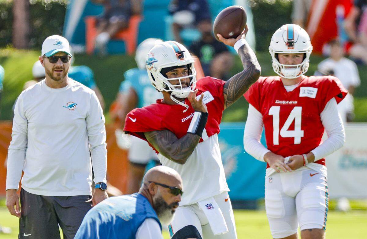 Miami Dolphins quarterback Tua Tagovailoa (1) sets up to pass as quarterbacks / pass game coordinator Darrell Bevell and quarterback Quinn Ewers (14) watch during an NFL football joint practice with the Jacksonville Jaguars.