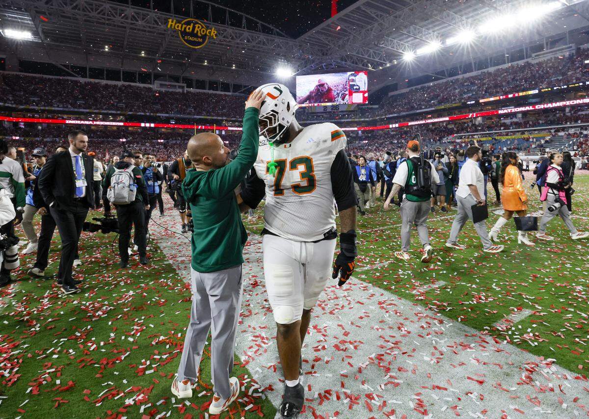 Miami Hurricanes offensive lineman Anez Cooper (73) is consoled on the field after the Canes are defeated by the Indiana Hoosiers in the College Football Playoff National Championship Game at Hard Rock Stadium in Miami Gardens, Florida, on Monday, January 19, 2026.