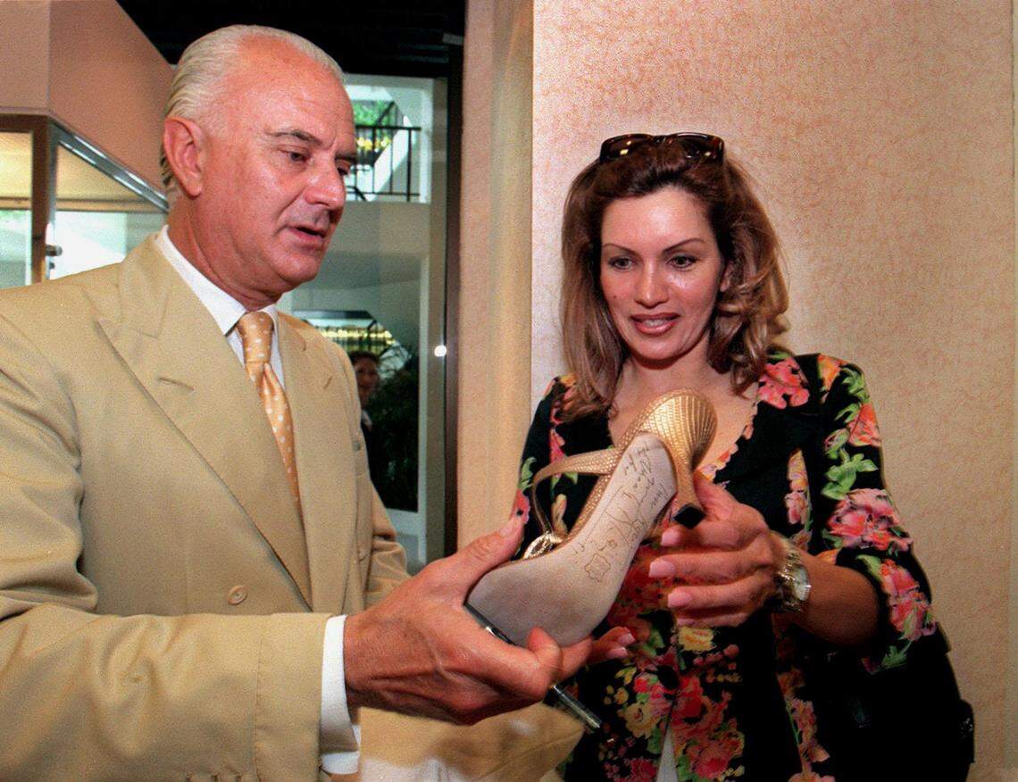 In this file photo from May 14, 1999, Spanish shoe designer Manolo Blahnik autographs a shoe for customer Rocio Conde from Atlanta who came to the Neiman Marcus shoe department at Bal Harbour to see the designer in person and to buy some shoes from the Blahnik collection.