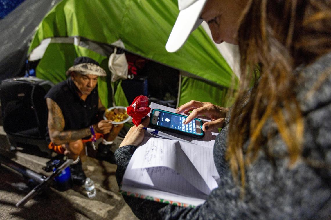A Hermanos de la Calle volunteer takes down the information of a unhoused man in hopes of getting him into a shelter during a food distribution event on NW 17th Street in Miami, Florida, on Friday, December 22, 2023.