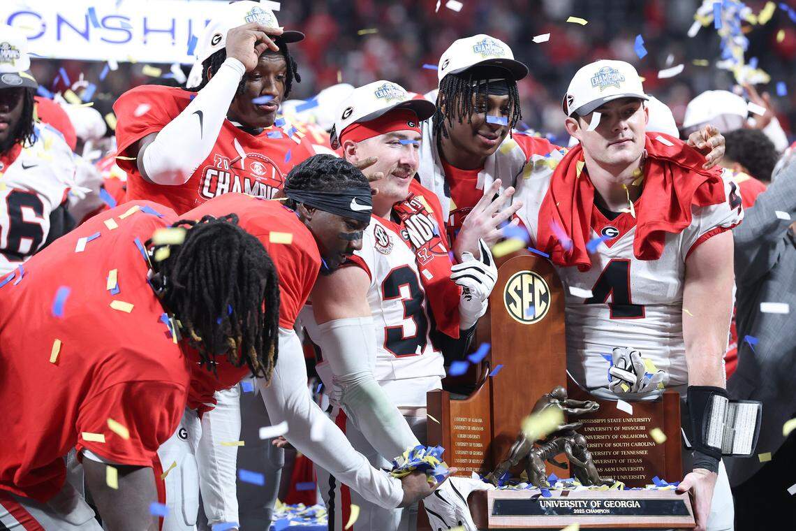 ATLANTA, GEORGIA - DECEMBER 06: Cash Jones #32 and Oscar Delp #4 of the Georgia Bulldogs hold the 2025 SEC Championship trophy after defeating the Alabama Crimson Tide 28-7 at Mercedes-Benz Stadium on December 06, 2025 in Atlanta, Georgia. (Photo by Kevin C. Cox/Getty Images)