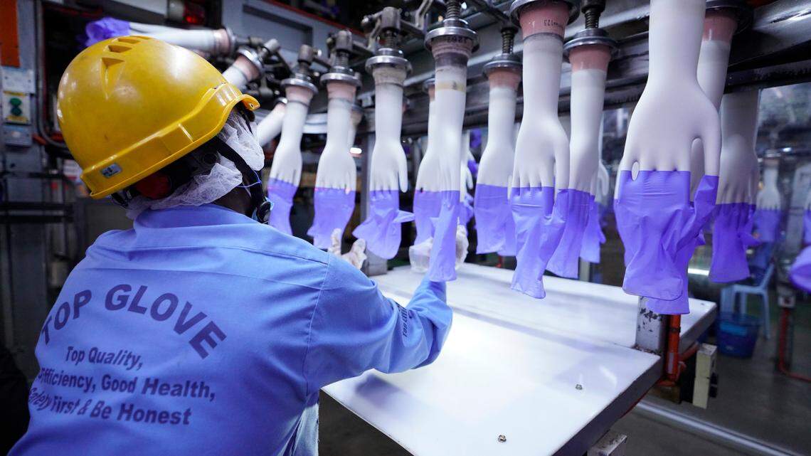 In this Wednesday, Aug. 26, 2020, file photo, a worker inspects disposable gloves at the Top Glove factory in Shah Alam on the outskirts of Kuala Lumpur, Malaysia. Malaysia’s Top Glove Corp., the world’s largest rubber glove maker, said Tuesday it expects a delay in deliveries after it was hit by a coronavirus outbreak that affected thousands of workers. (AP Photo/Vincent Thian)
