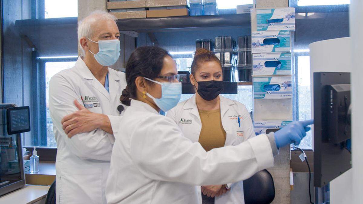 Investigadores de la Universidad de Miami han estado rastreando las variantes del SARS-CoV-2 mediante la secuenciación genómica. En esta foto, el Dr. David Andrews, profesor adjunto de la Facultad Miller de Medicina de la Universidad de Miami, revisa los datos con la tecnóloga médica principal Ranjini Valiathan y Paola Pagan, directora ejecutiva de Operaciones de Laboratorio.