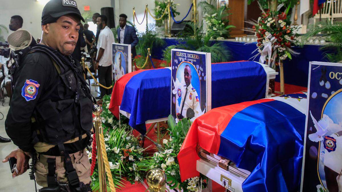 A police officer cries next to coffins containing the bodies of three police officers killed in the line of duty, at the Police Academy in Port-au-Prince, Haiti, Tuesday, Jan. 31, 2023. The officers were killed in an ambush by gang members in the capital on Jan. 20.