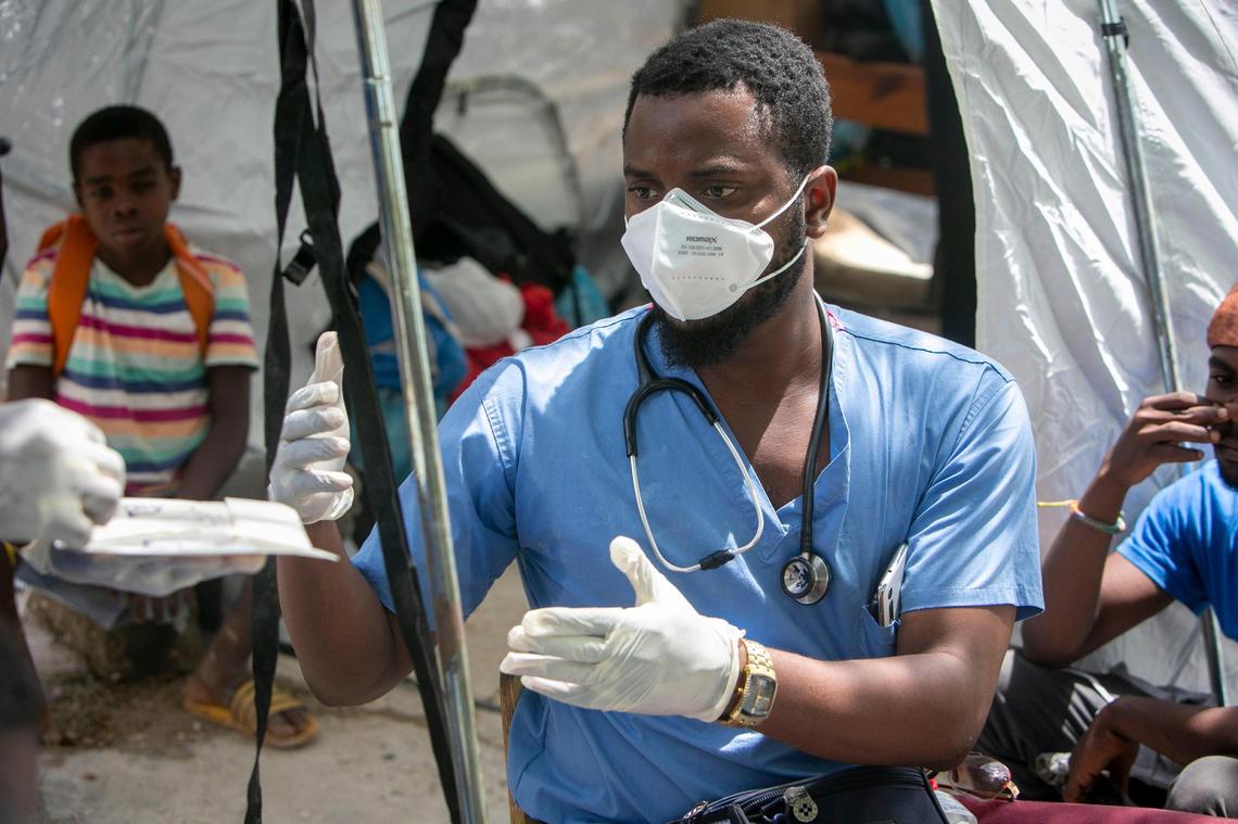 Marceline, Haiti, August 18, 2021 - Dr. Wonston Raphael asks a colleague for additional gloves while taking care of a patient. Doctors Timothee Jean-Jacques, Wonston Raphael, Ruben Misaac Pierre, Stanley Ettenne, Medgina Felix and Physical Therapist Rose-Milord Celestin, used their own money to buy medicals supplies and transported themselves and the supplies to Marceline to help out the victims of the earthquake.