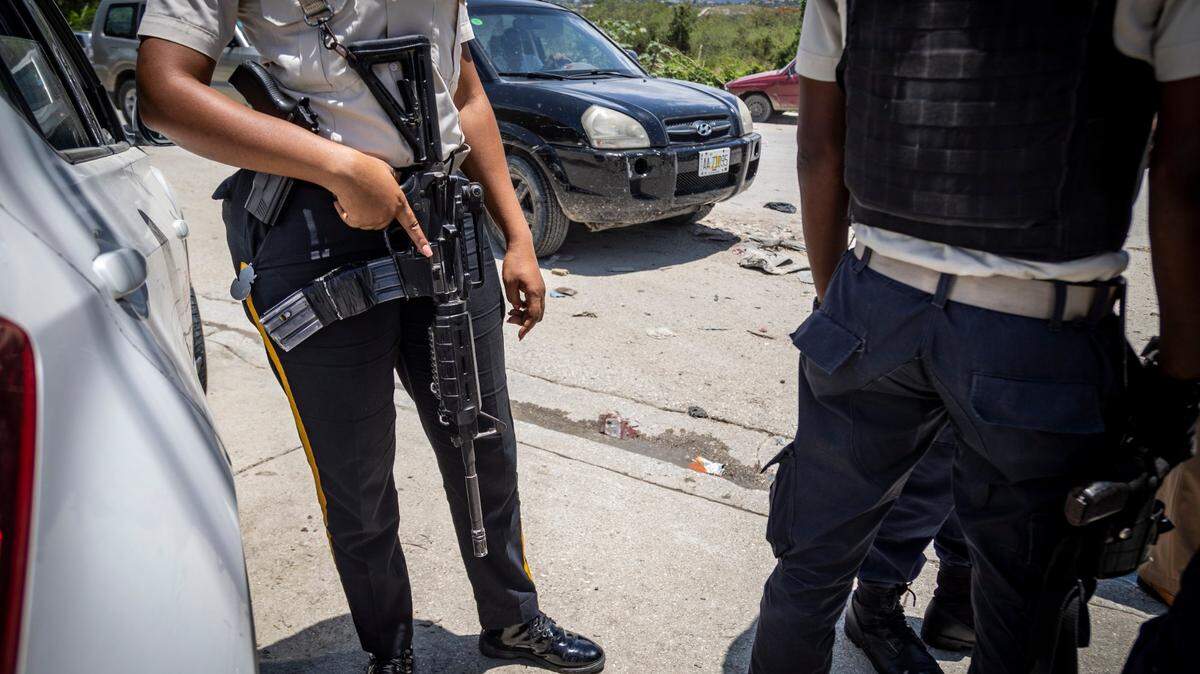 Port-au-Prince, June 23, 2022 - A heavily armed Haitian policewoman keeps watch as Commissioner Livenston Gauthier (not pictured) talks to some young police officers at a check point near the U.S. Embassy in Port-au-Prince.