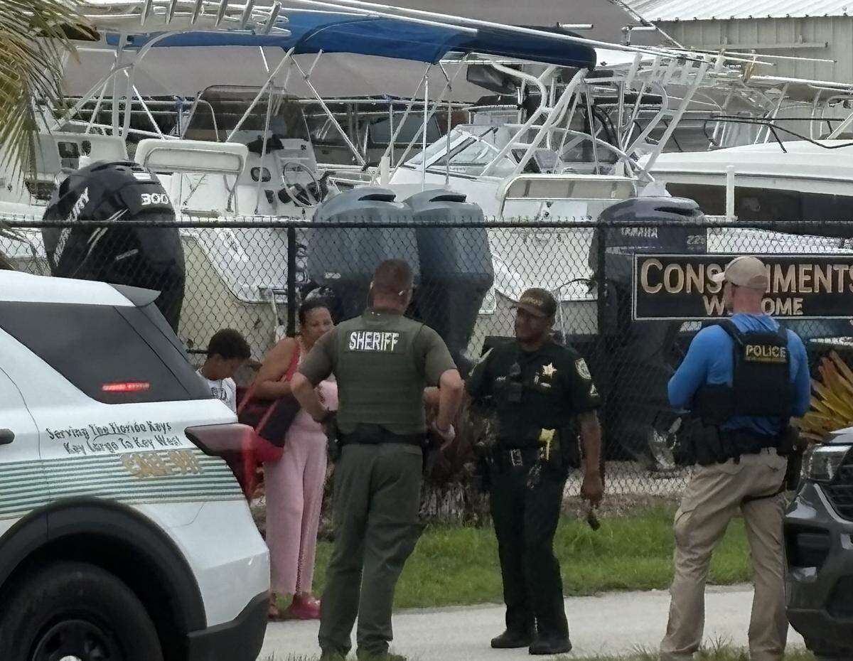 Local, state and federal law enforcement officers stood with a small group of recently arrived migrants in the Florida Keys Thursday afternoon.