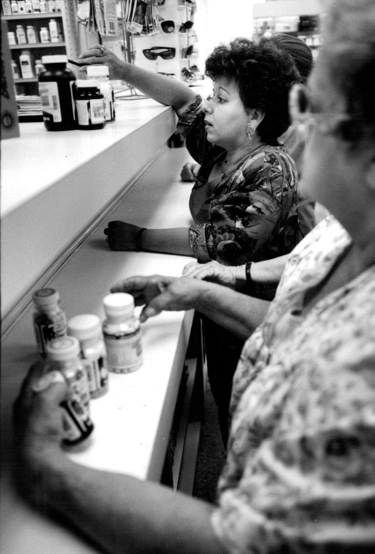In the Miami Price Pharmacy, owned by Fidel Castro’s sister Juanita Castro, Maritza Valladares (1t) presents vitamins to the cashier for Purchase While Hemelina Gomez looks on. Lots of Miami residents are purchasing vitamins to be sent to Cuba because many of that island’s residents diets do not provide the necessary vitams they need to be healthy.