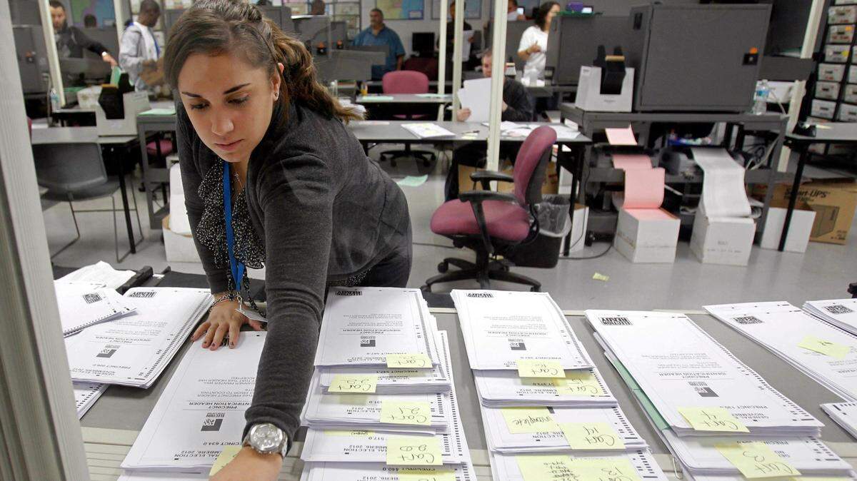 A Miami-Dade Elections worker marks a group of absentee ballots. Florida’s primary elections for governor and other offices is Aug. 28, although absentee voting has already begun.