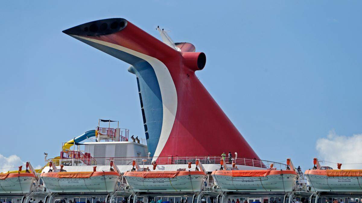Carnival Fascination passengers look out from their balconies at PortMiami as the coronavirus pandemic continues on March 17, 2020.