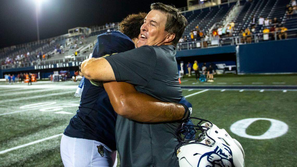 Florida International University defensive lineman Davon Strickland (99) is hugged by head coach Mike MacIntyre after defeating Louisiana Tech University 42-34 during double-overtime of an NCAA Conference USA football game at Riccardo Silva Stadium in Miami, Florida, on Friday, October 28, 2022.