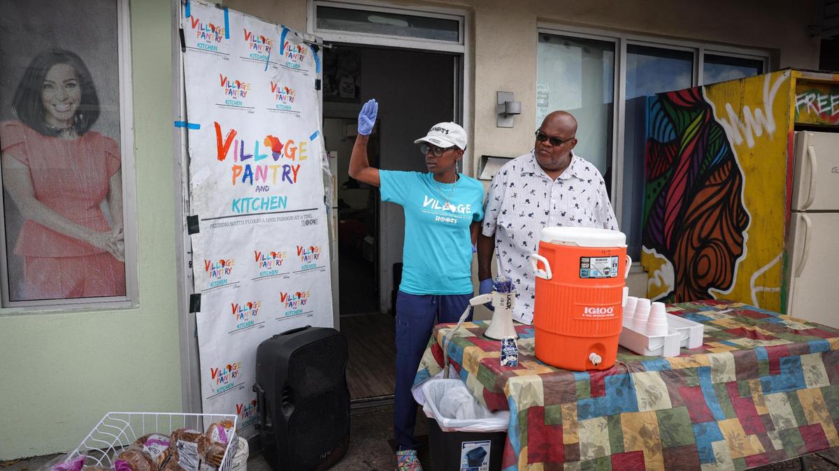 Sherina Jones (izquierda), fundadora de Village FREEdge, saluda a uno de los últimos miembros de la comunidad que fue  a recoger una bolsa de comida de manos de Willy Harris (derecha), de la despensa de alimentos, el 9 de febrero de 2023, en Liberty City.