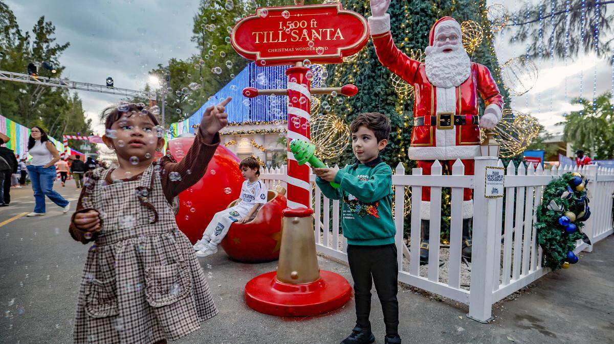 Gianna Parada, 3, and Sebastian Barragan, 4, play with bubbles during opening night at Christmas Wonderland at Tropical Park, a Miami-style holiday celebration of flavor and culture in Miami, Florida on Thursday, November 13, 2025.