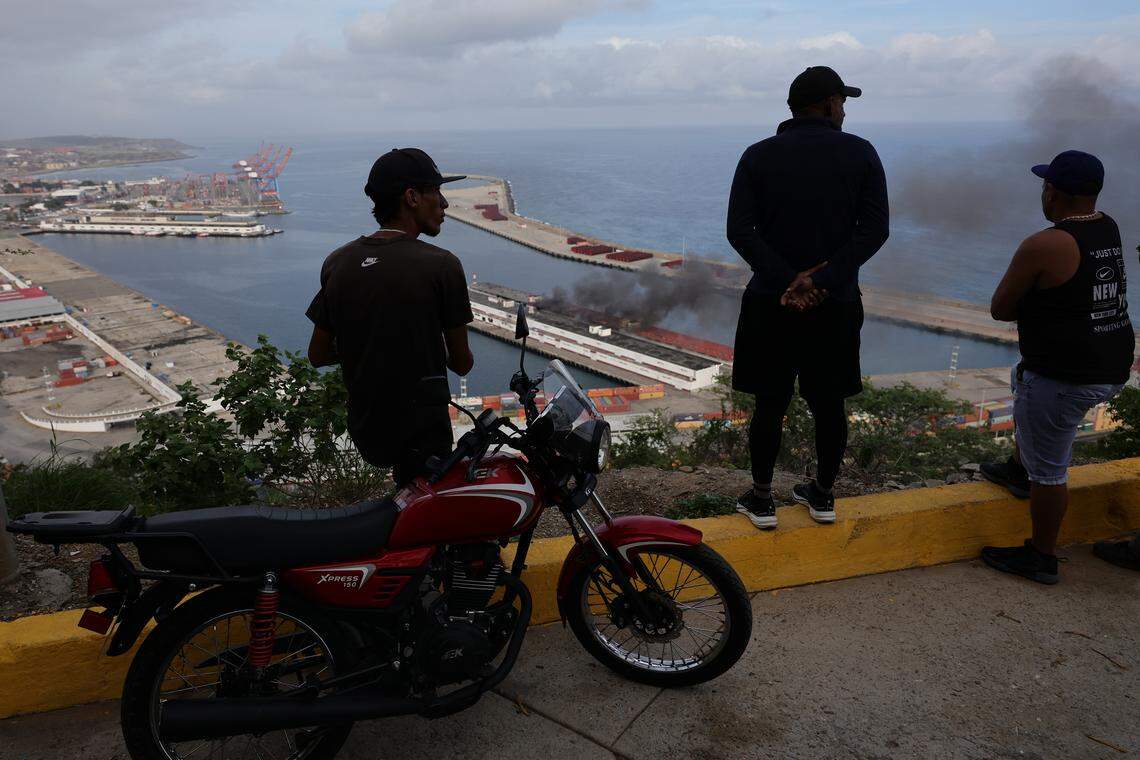 People watch the smoke rising from Port of La Guaira after explosions and low-flying aircraft were heard on January 03, 2026 in Caracas, Venezuela.