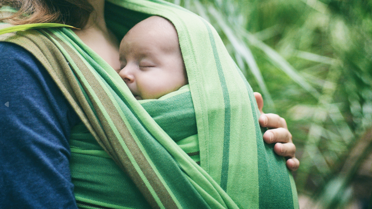 mother holding baby in a sling