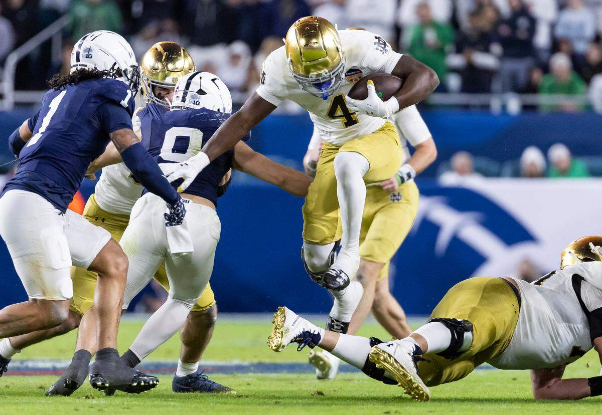 Notre Dame Fighting Irish running back Jeremiyah Love (4) runs with the ball as Penn State Nittany Lions safety Jaylen Reed (1) defends in the second half of their NCAA Playoff Semifinal Capital One Orange Bowl football game at Hard Rock Stadium on Thursday, Jan. 9, 2025, in Miami Gardens, Fla.