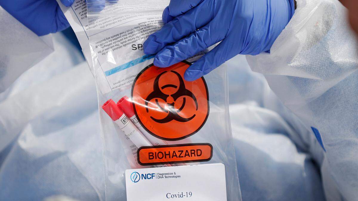In this stock photo, registered medical assistant Elaine Lomax handles a nasal swab specimen after it was collected at a drive-through COVID-19 testing site Thursday, April 16, 2020, in St. Louis.
