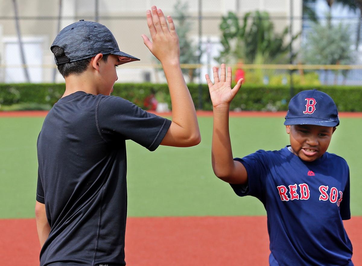 Baseball buddies Noah Katzman, 14, left, shares a high-five with  Garth Fowler, 9, right, who has autism, as they participate in North Miami Beach Little League Buddies program at Pelican Park in Sunny Isles Beach on Sunday, Nov. 4, 2018.