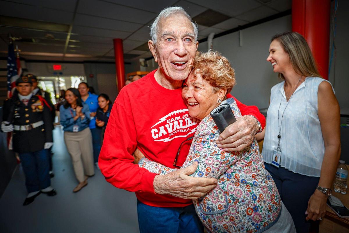 Coral Gables High School’s Daniel Finora, 90, is hugged by math teacher Niurka Prado as he arrives to see former students and fellow teachers celebrate his retirement after 65 years at the school.