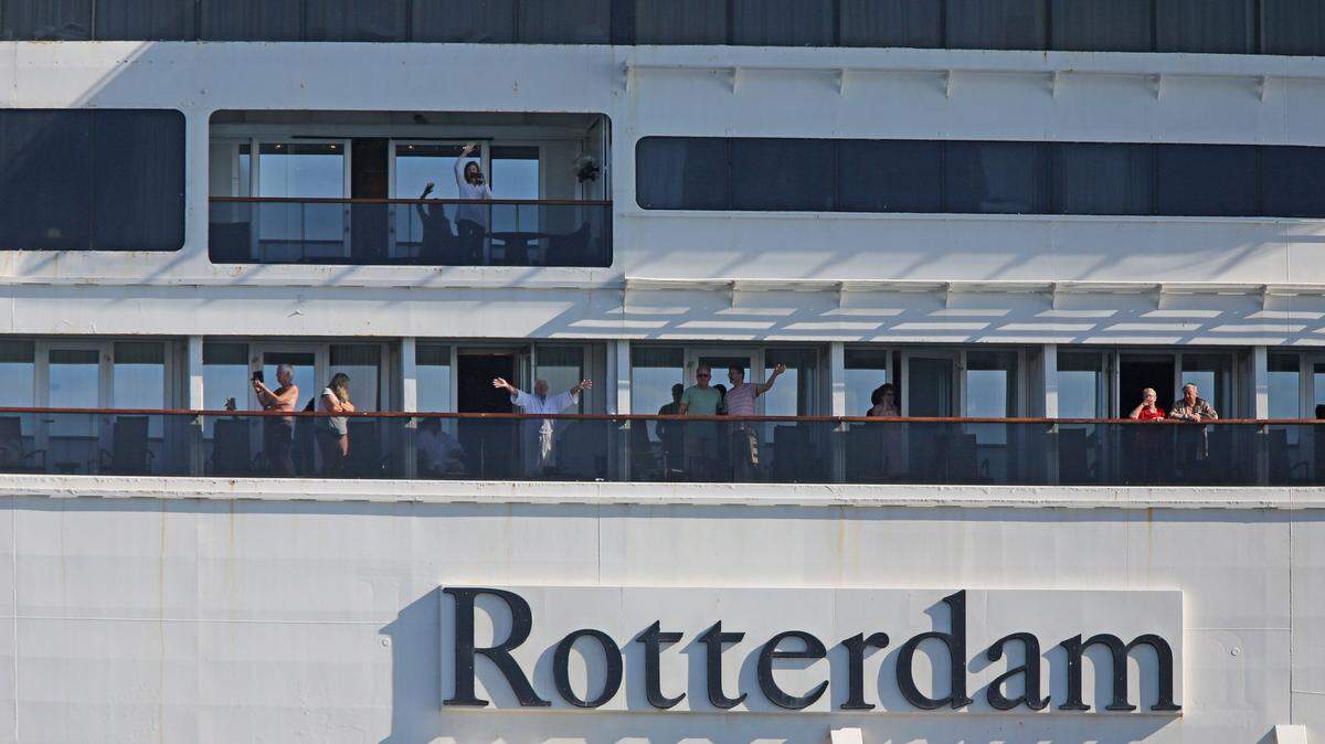 Passengers aboard the Rotterdam wave as their ship is escorted into Port Everglades on April 2, 2020. The Rotterdam followed its sister ship, the Zaandam, into Port Everglades after the Zaandam spent 12 days at sea searching for a place to dock with COVID-19 patients onboard.