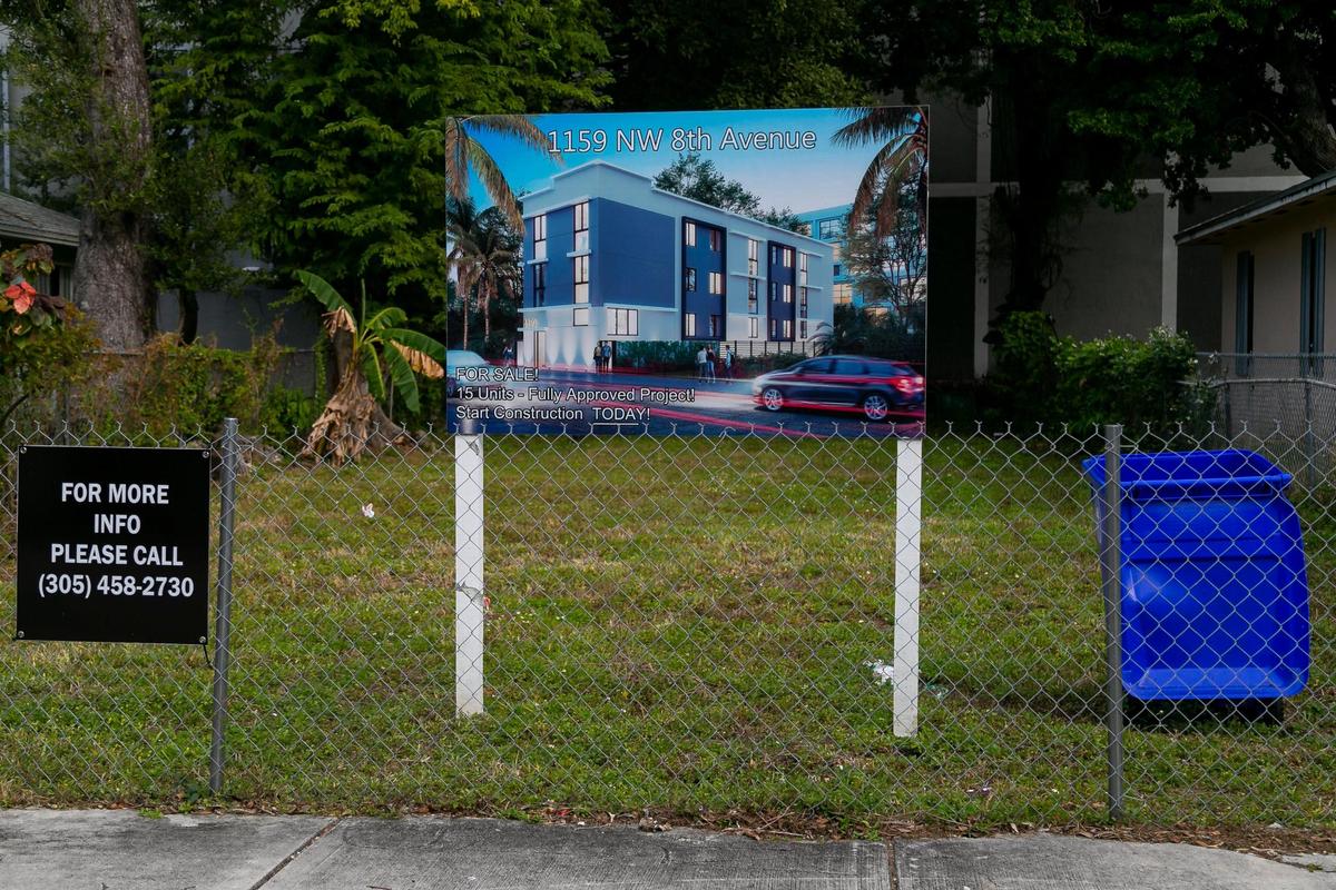 A developer’s sign with a rendering of a proposed new apartment building stands in a vacant lot between two homes built by Habitat for Humanity in Miami’s Highland Park neighborhood.