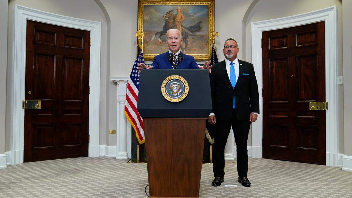 President Joe Biden speaks about student loan debt forgiveness in the Roosevelt Room of the White House, Wednesday, Aug. 24, 2022, in Washington. Education Secretary Miguel Cardona listens at right. (AP Photo/Evan Vucci)