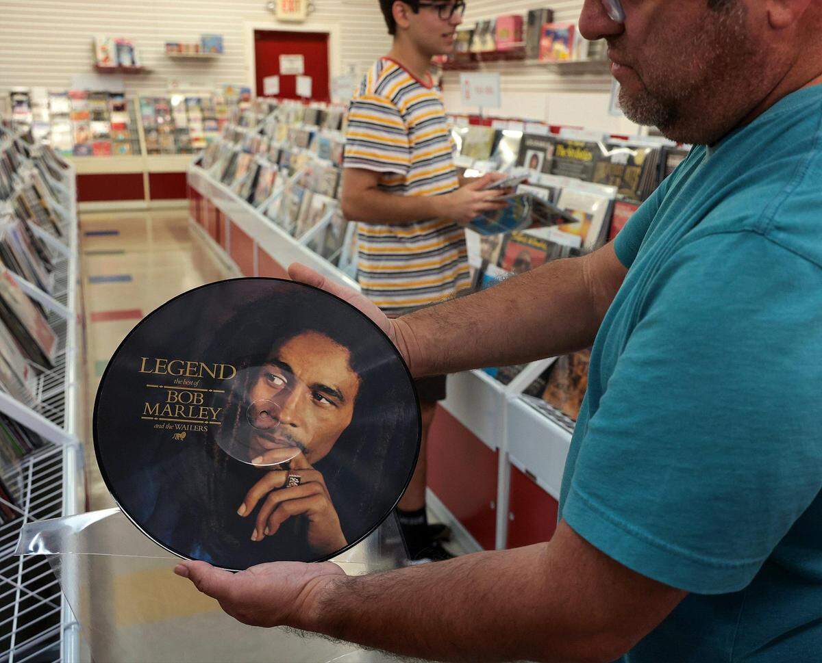 Eli Ramos, 50, right, holds a picture-disc copy of Bob Marley’s “Legend” album while shopping with his son, Alessandro Ramos, 16, at Museo del Disco.