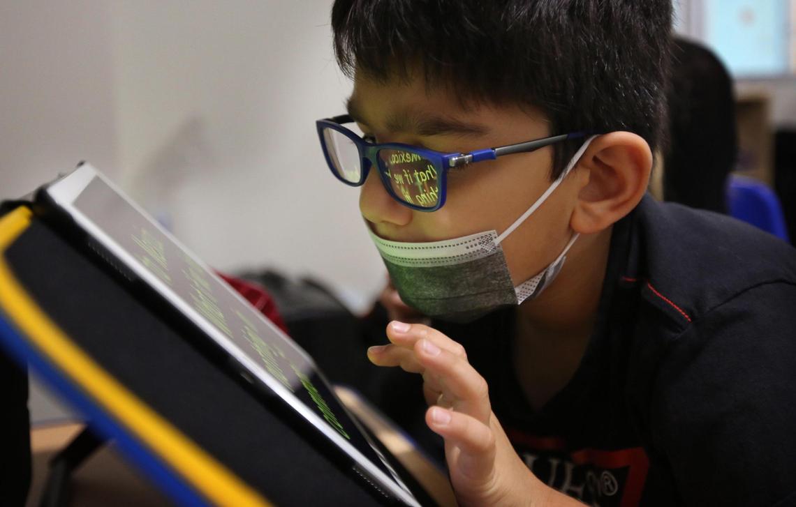 Miami Lighthouse for the Blind and Visually Impaired second-grade student, Lorenzo, reads a story aloud using an iPad with enlarged, bright yellow letters on a black background on Monday, Dec. 6, 2021. Lorenzo is a student who is part of a new initiative Miami Lighthouse is using to help kids diagnosed with CVI, the No. 1 cause of bilateral visual impairment in children in the developed world.