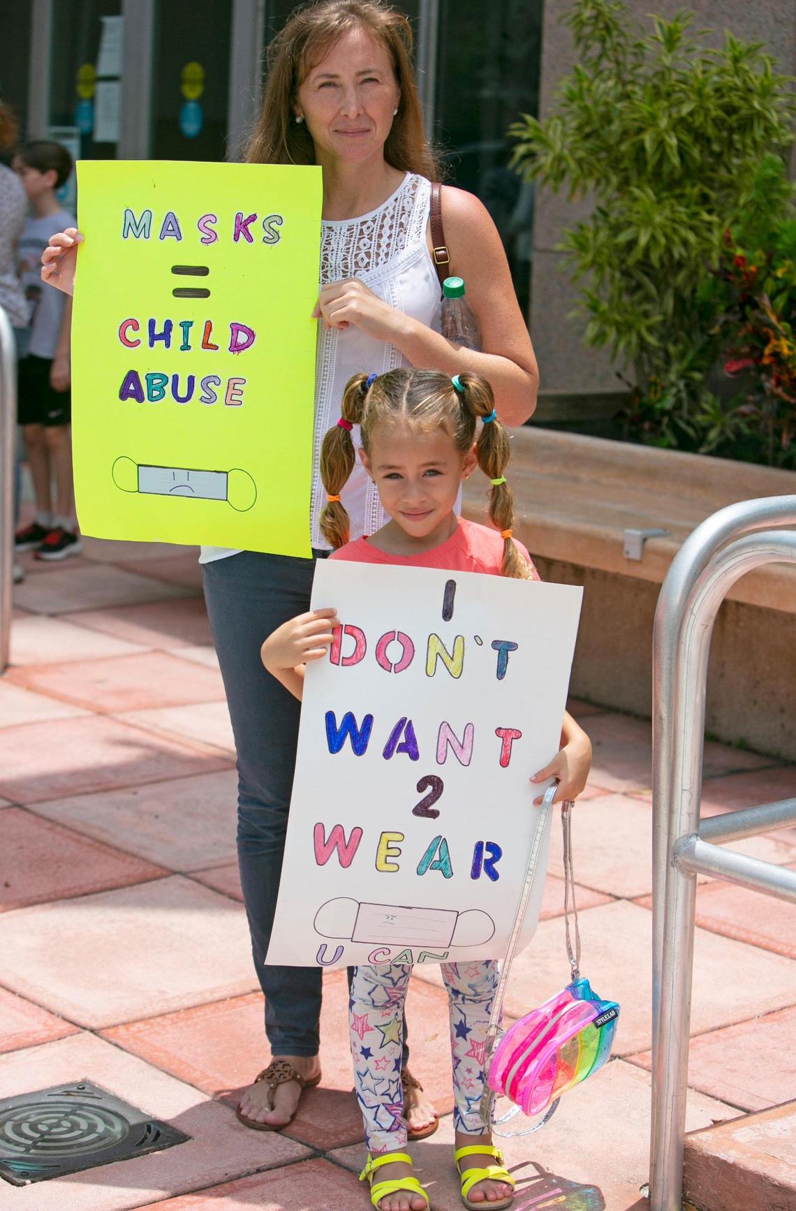 Barbara Rodas holds signs with her 6-year-old daughter, Athena Coletti, outside of the Kathleen C. Wright Administration Building on Tuesday, July 27, 2021. Athena was planning to speak in front of the Broward School Board during a discussion on COVID-19 safety precautions and potential mask mandates for the upcoming school year.