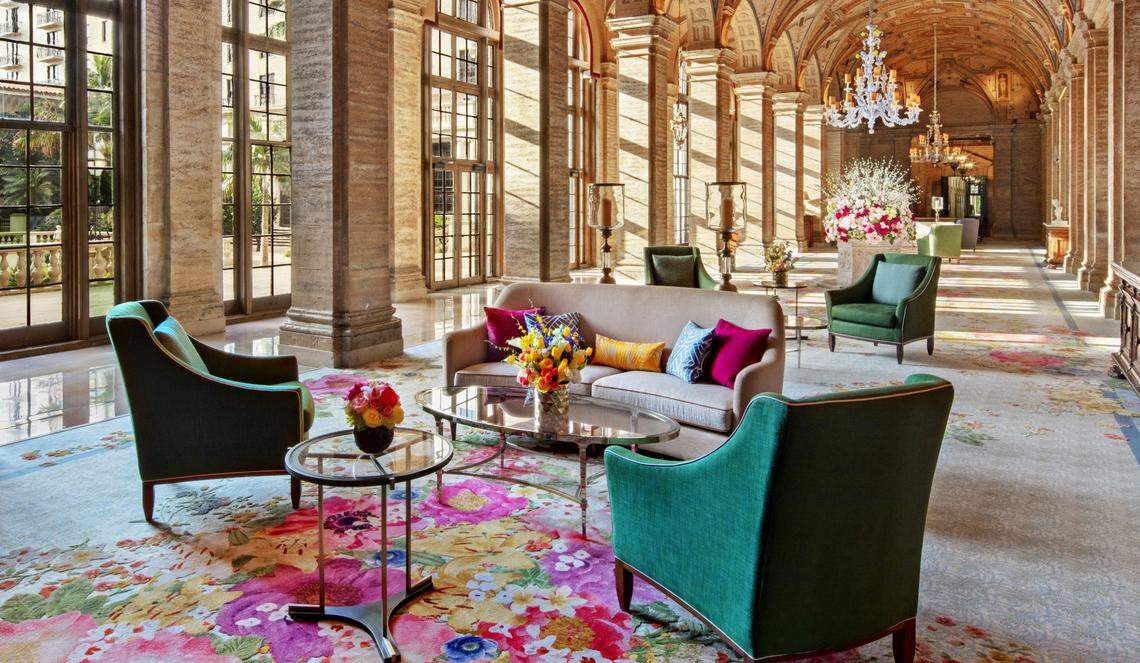 Flowers decorate a lobby full of relaxing furniture with ornate floral carpeting and floor-to-ceiling windows at The Breakers resort in Palm Beach.