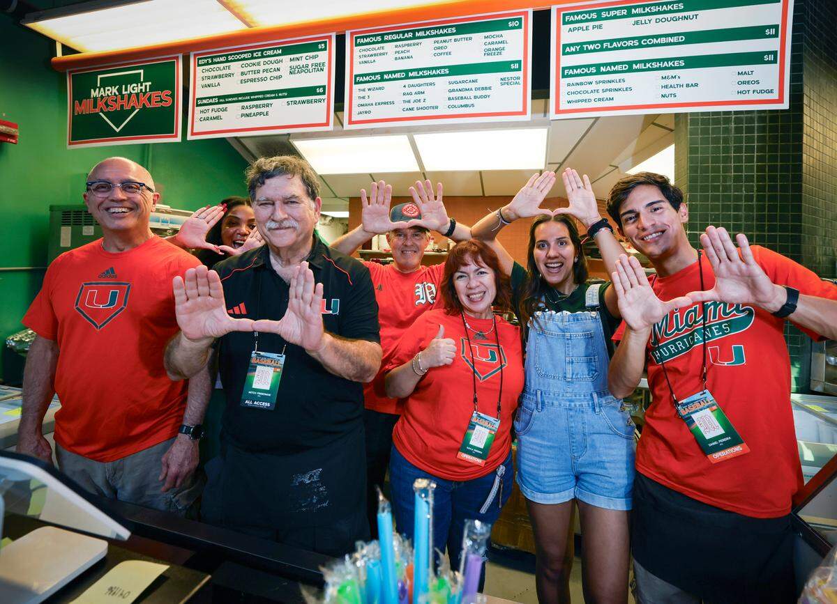 Mark Light Shake owner, Mitch Freedman, flashing the U on the left, serves up shakes with his long time friend Luis Castillo, at far left, and Castillo’s family members, Francisco Pereira, Keyla Manrique, Michelle Pereira and Daniel Pereira, at Alex Rodriguez Park at Mark Light Field on the University of Miami campus in Coral Gables, Florida on Friday, February 14, 2025.