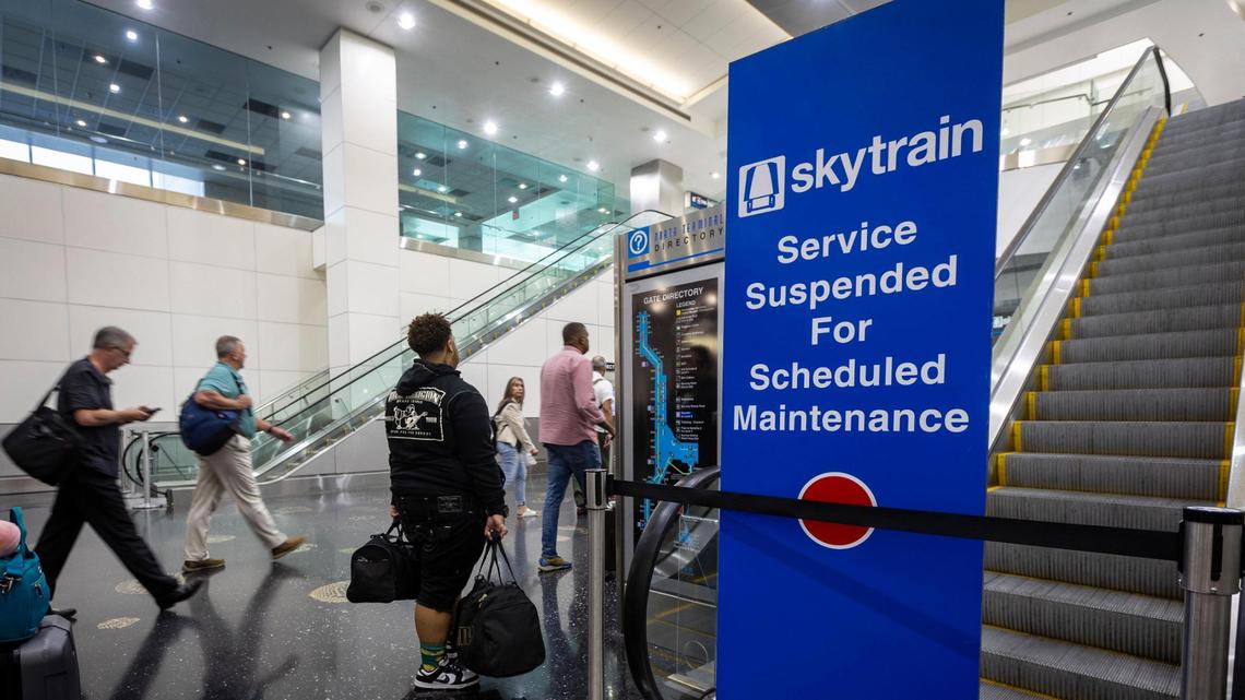 People with their luggage walk past a closed entrance to the Skytrain on Concourse D at Miami International Airport, Wednesday, Sept. 27, 2023. The Skytrain is down indefinitely and a courtesy shuttle is the only option passengers have besides walking to get from one end of the terminal to the other.
